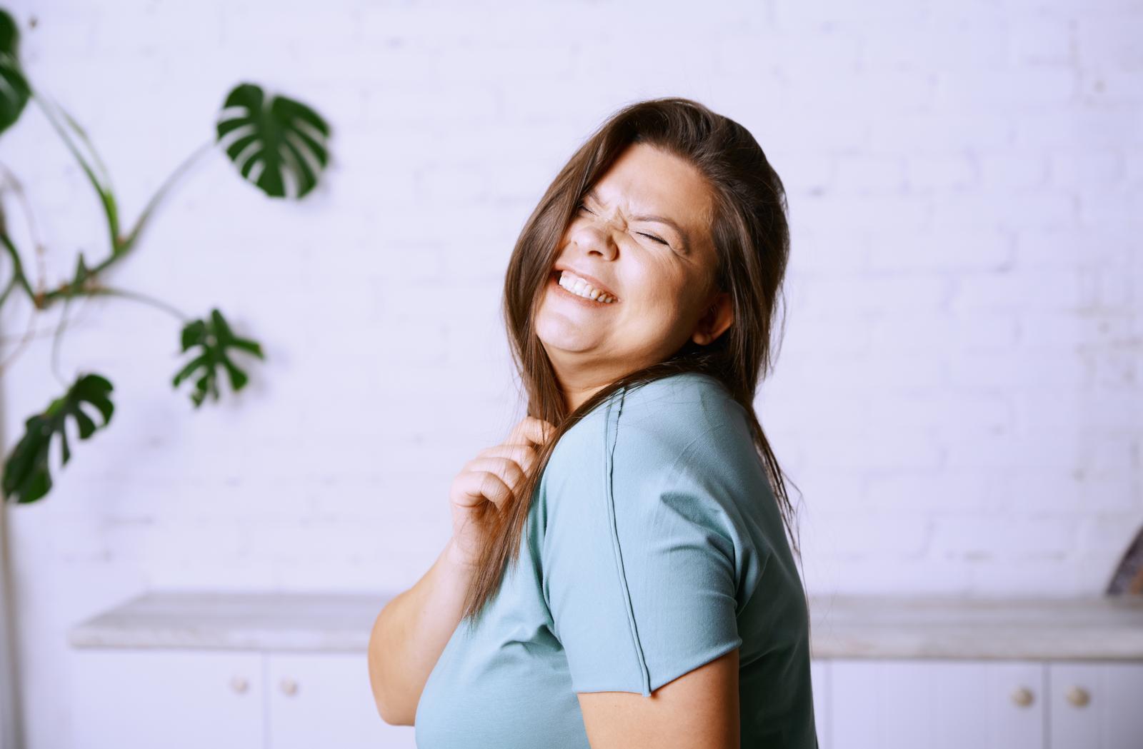 happy model clasping her hair looking over her shoulder smiling.