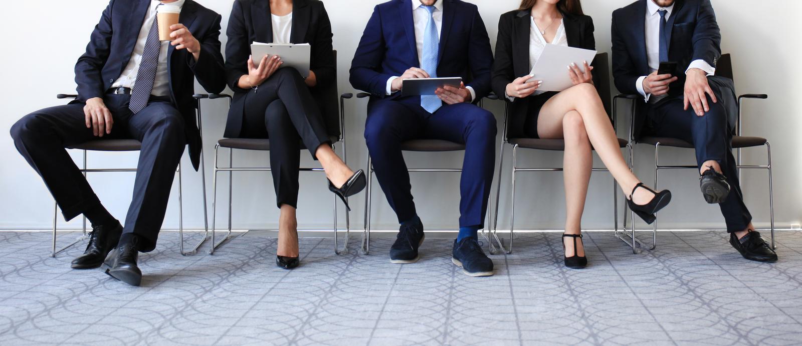 a row of professionally dressed people waiting for an interview.