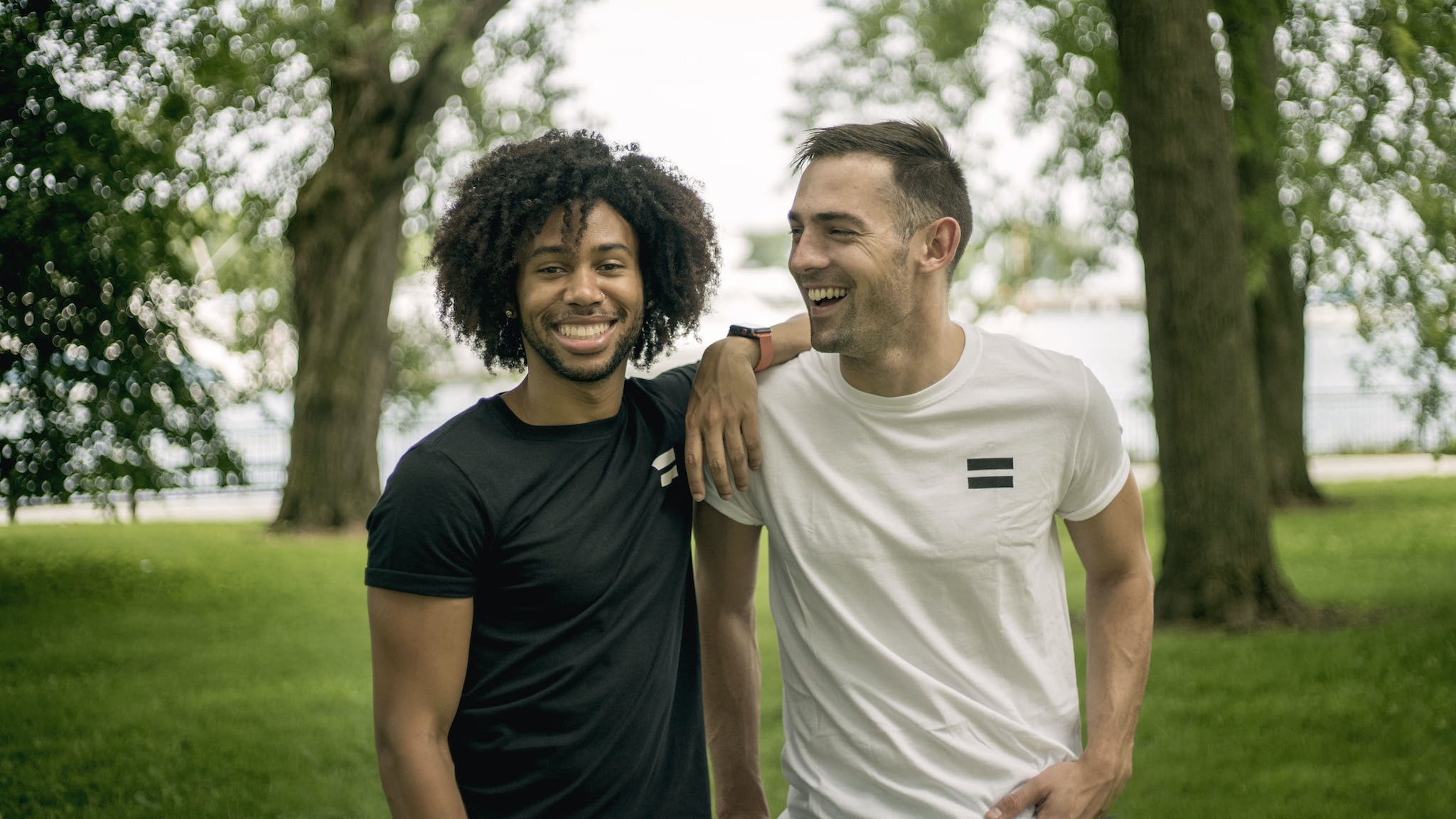 Two Men Standing on Grass Field smiling.